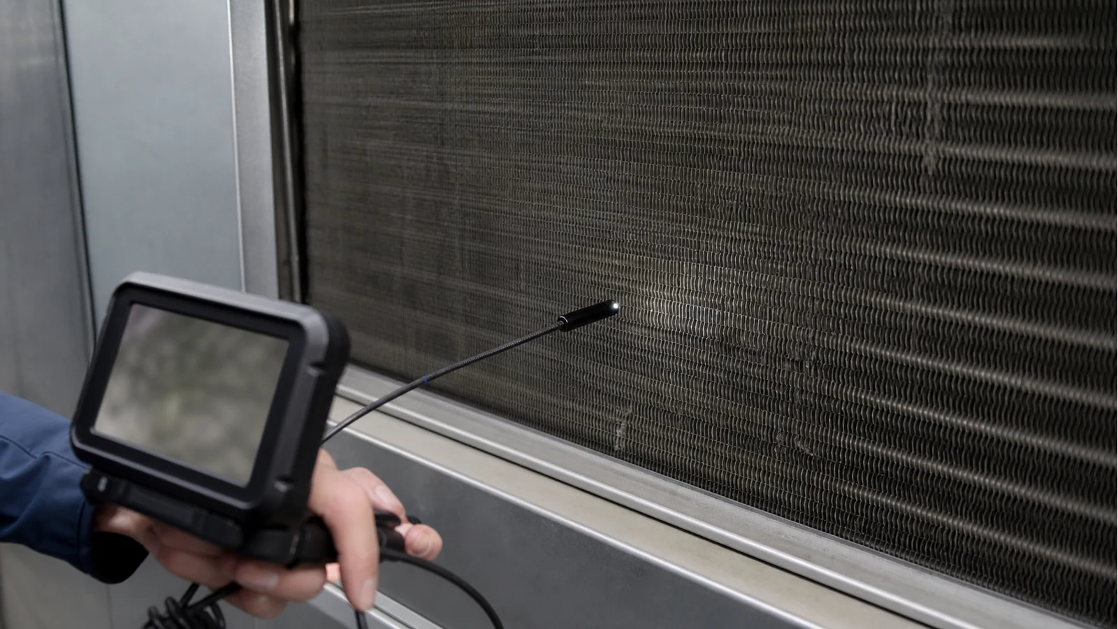 Inspection camera probe approaching an evaporator coil face for fouling documentation